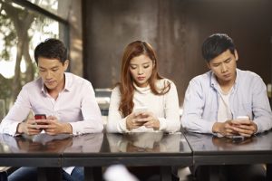 young people playing with smartphones and ignoring each other.